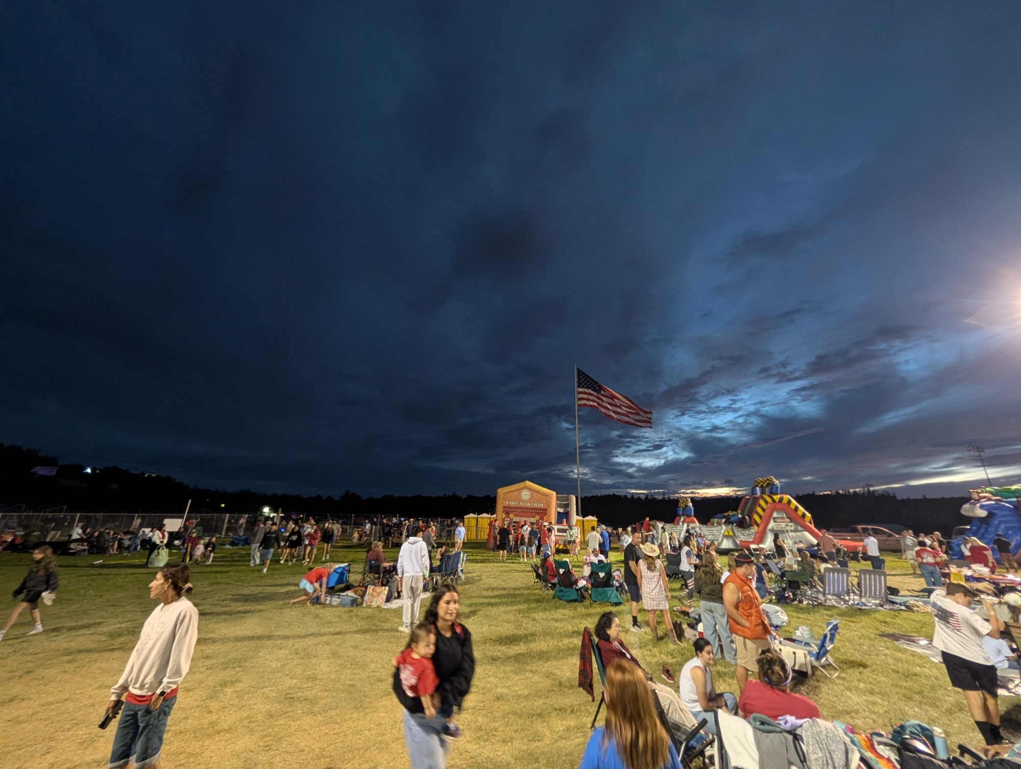 The flag over the fireworks field at Mogollon High, storm-blue sky behind โ 4th of July in Heber